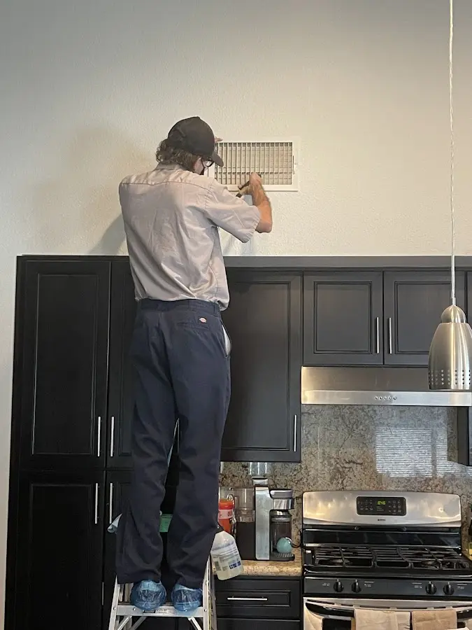 Technician inspecting an air vent during HVAC service in Watauga